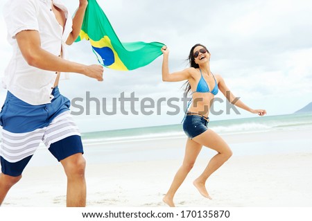 Latino hispanic couple are Brasil fans and hold flag having fun together