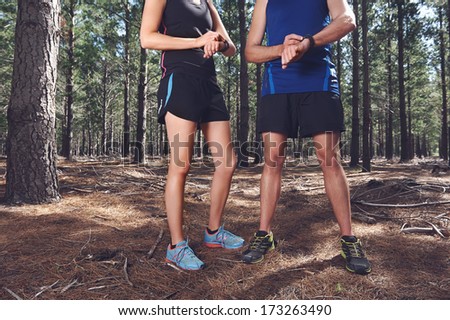 Trail running couple check time on their gps watch for tracking pace