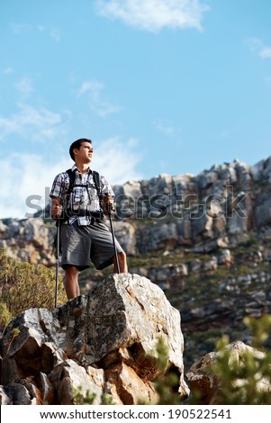 A hiker male standing on a mountain cliff in a mountain range with copyspace