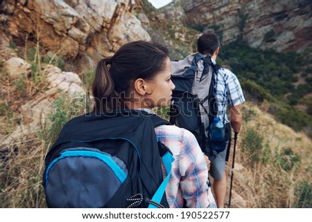 Back view of a couple walking along a hiking trail in the wilderness