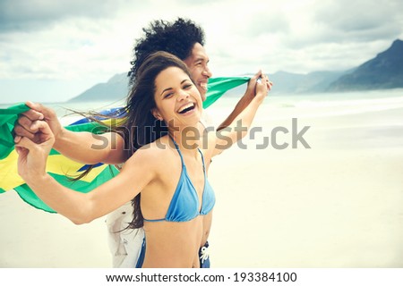 Latino hispanic couple are Brasil fans and hold flag having fun together