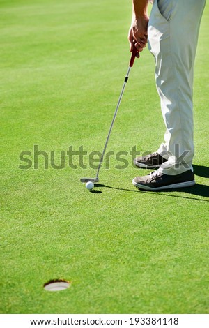Golf man putting on green and aiming to sink golf putt shot on course