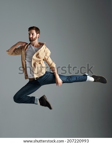 Fashion model man with hipster beard jumping and having fun in studio