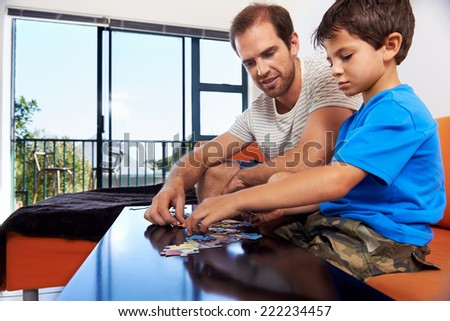 A dad and his son bonding over piecing a puzzle together