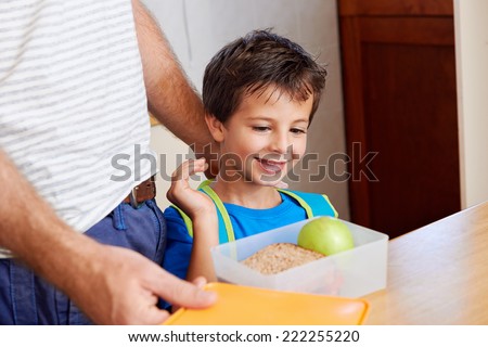 happy young boy with dad and healthy food apple in lunch box for school