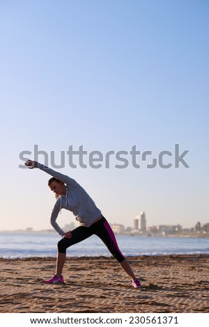 woman stretching leg muscle before early morning run workout on beach