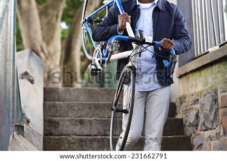 Man carrying bicycle down some stairs in city on his way to work