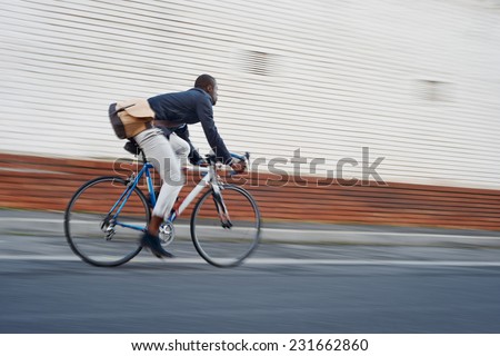 Black african mad riding bicycle in urban city commuting with speed and hipster trendy transportation