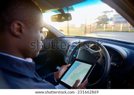 Man using GPS navigation on tablet computer to find address to drive in his car