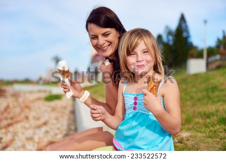 Mom and daughter enjoy fun ice cream at the beach smiling laughing joy on summer vacation