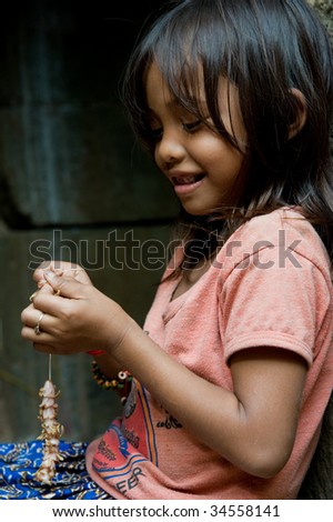 SIEM REAP, CAMBODIA - CIRCA JANUARY 2009: A young unidentified girl is making a souvenir necklace out of flowers CIRCA JANUARY 2009. Allegedly, many Cambodian children help support their families.