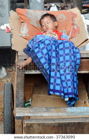 JAKARTA, INDONESIA - SEPTEMBER 20: A young street child sleeps in a trash cart on Hari Raya, the end of a month of fasting called Ramadan Jakarta September 20, 2009 in Jakarta.