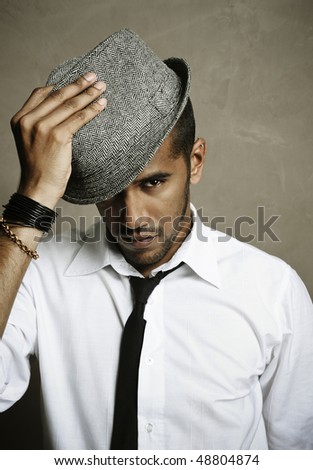 Male model stares at camera with hand on hat