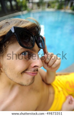 Tanning man looks at camera as he enjoys the hotel resort