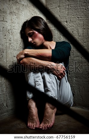 Abused woman in the corner of a stairway comforting herself