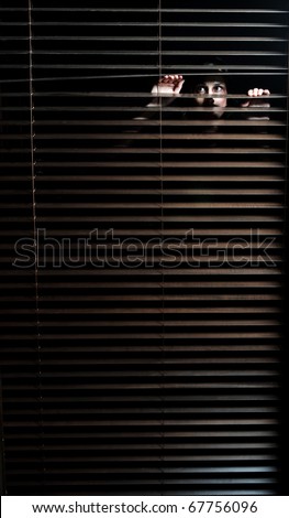 Mysterious woman pulls the blinds apart to see the outside world