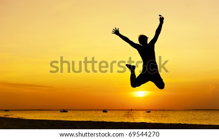 Happy jump during sunset or sunrise while on holiday at the beach.