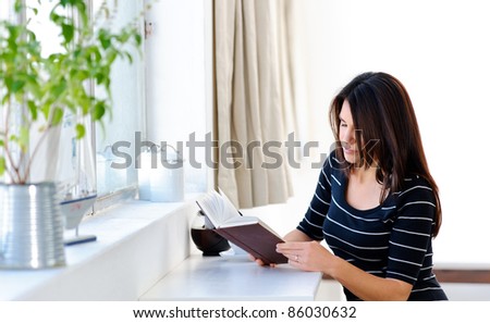 Pretty caucasian woman relaxing indoors with a book and tea