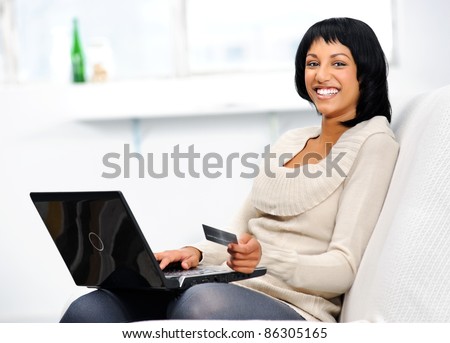 Smiling indian woman with laptop and credit card at home