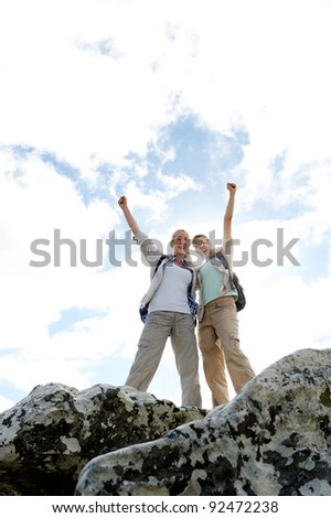 successful and happy hiking women on top of a rock