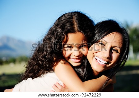 mom and daughter have fun outdoors, smiling and piggyback in the sunshine