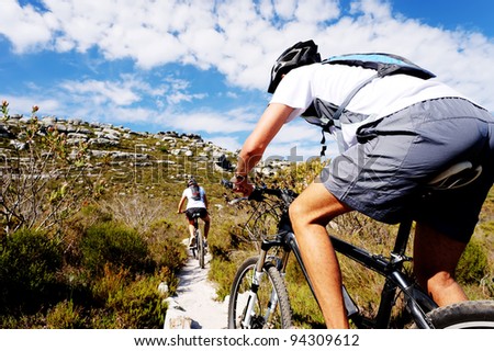 Wide angle view of a cyclist riding a bike on a nature trail in the mountains. two people living a healthy lifestyle