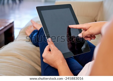 Woman at home relaxing on sofa couch reading email on the tablet computer wifi connection