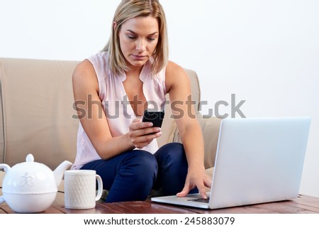 Woman sitting on sofa couch checking accounts and shopping online at home