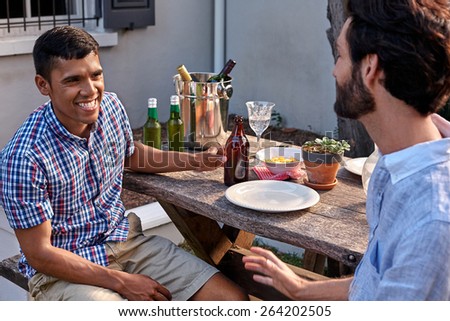 group of friends having outdoor garden dinner party with beer drinks