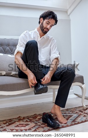 professional man getting ready for work putting smart shoes on and tying shoelaces at home