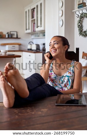 young woman using mobile phone with feet up relaxing