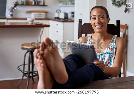 young woman using tablet computer with feet up relaxing