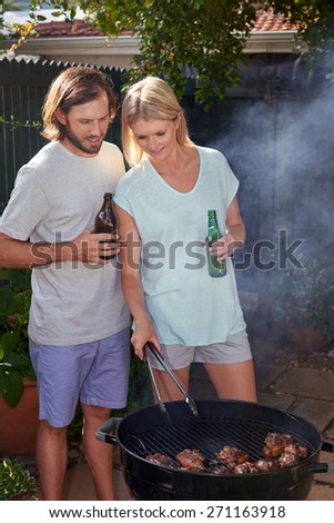 Women helping boyfriend husband at outdoor garden barbecue with tongs and beer