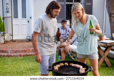 Women helping boyfriend husband at outdoor garden barbecue with tongs and beer