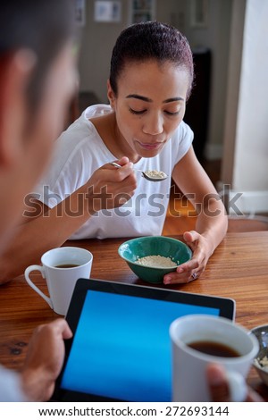 couple enjoying a healthy morning breakfast cereal with tablet computer in kitchen at home
