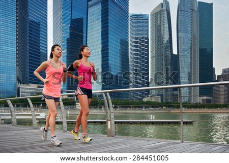 asian chinese sporty running women working out jogging outdoors along urban city harbor sidewalk morning