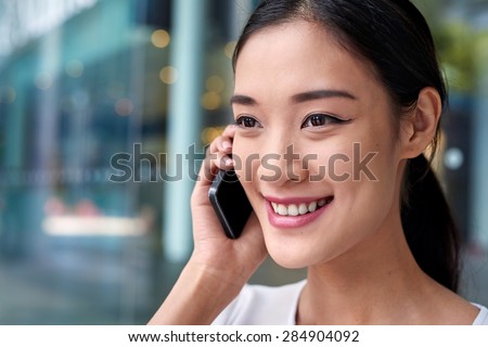 happy asian chinese business woman talking on mobile cell phone at work
