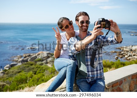 couple takes a selfie with a beautiful ocean background using a digital camera