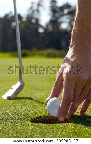 golf man taking ball out hole after making birdie