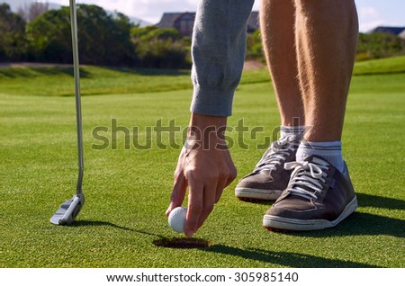 golf man taking ball out hole after making birdie
