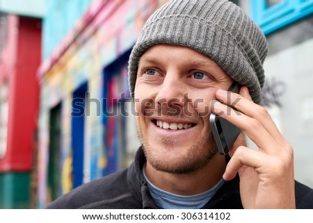 young happy caucasian adult man wearing beanie hat talking on mobile cell phone.