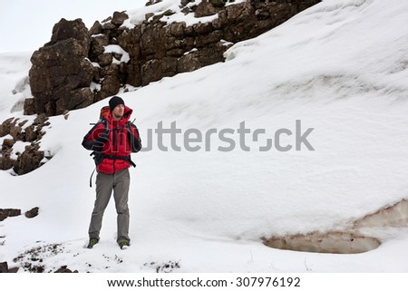 Active adventurous hiking man trekking by the river, cold winter landscape snowy icy wilderness