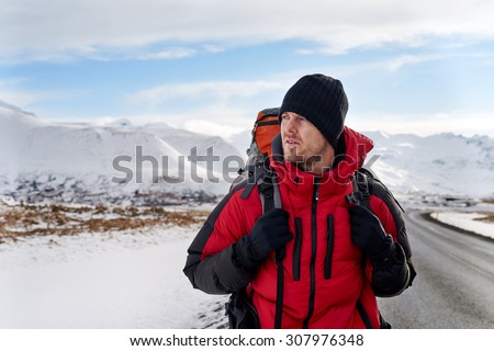 Backpacker traveling holiday on a budget walking along a empty road, in harsh winter snowy cold extreme conditions