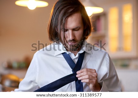 young professional man doing morning routine shirt and tie at home