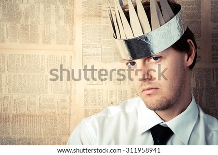 Man in shirt and tie with cardboard crown on head, image graded in vintage tone