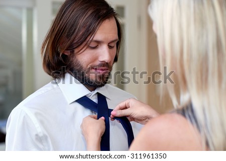 woman helping man with tie early morning for work formal event
