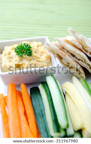 Vegetarian platter of raw carrots, corn, cucumber and celery sticks with chickpea dip and flatbread