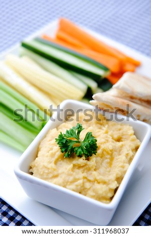 Colourful vegetarian platter of raw carrots, corn, cucumber and celery sticks with chickpea dip and flat bread