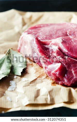 Raw bloody steak on butchers paper with dried herb and coarse salt, graded in dramatic colour tone
