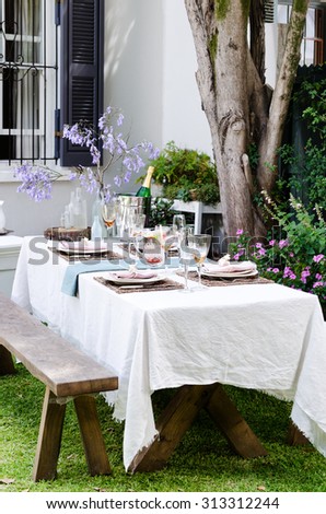 Simple rustic country style table setting for a party gathering in a casual outdoor garden setting